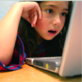 Photo of a child, with mouth wide open looking at a computer screen.