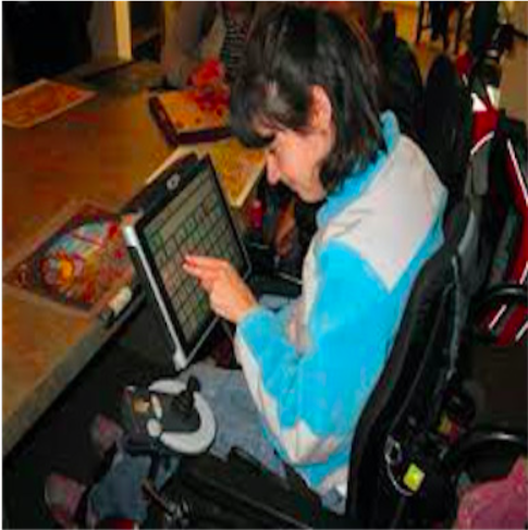 Photo of a young adult in a wheel chair using a speech generating device to communicate.